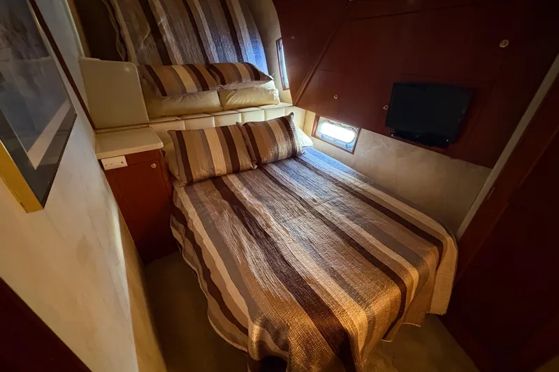 Slide: The Image of Cozy bedroom in 1996 Ocean Yachts 48 Super Sport with striped bedding and small window. - 24