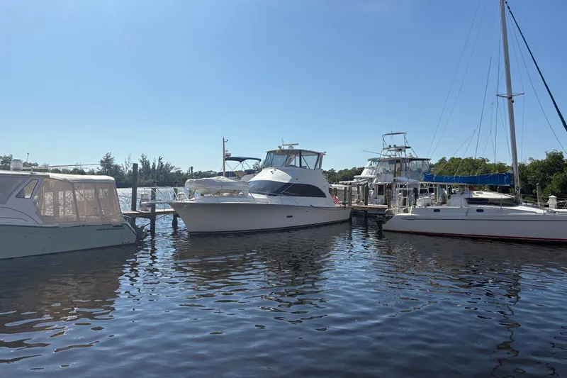 The Image of 1996 Ocean Yachts 48 Super Sport docked among other boats on a sunny day. - 0
