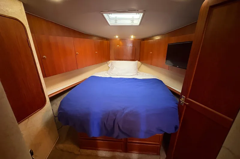 Slide: The Image of 1996 Ocean Yachts 48 Super Sport cabin with bed, wooden cabinets, and TV. - 26