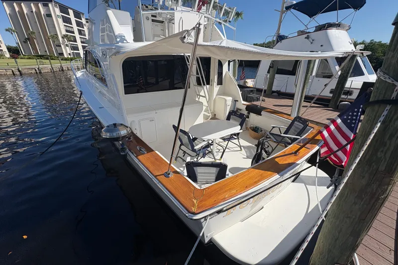 Slide: The Image of 1996 Ocean Yachts 48 Super Sport docked, featuring spacious deck and American flag. - 28