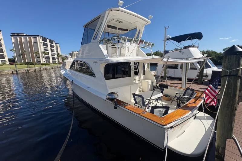 Slide: The Image of 1996 Ocean Yachts 48 Super Sport docked, featuring spacious deck and American flag. - 29