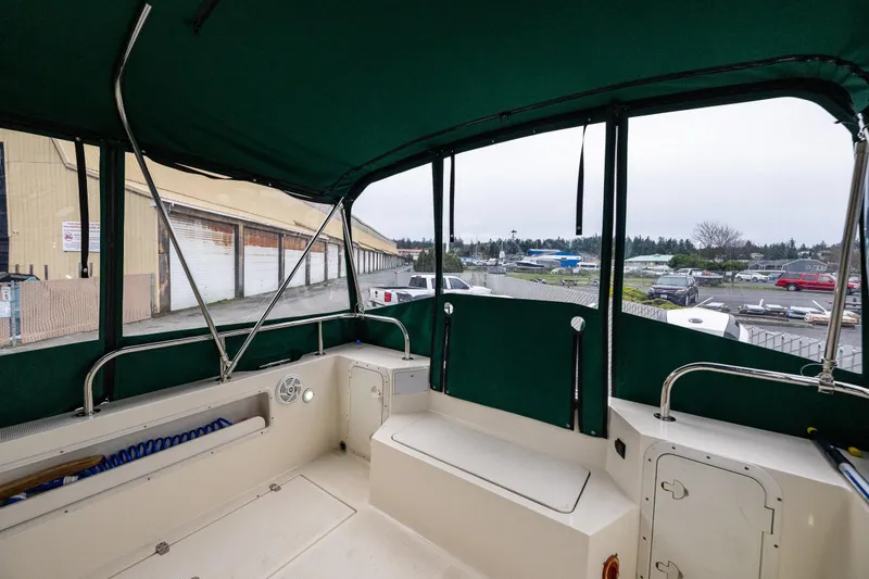 Slide: The Image of 2006 C-Dory 25' Tomcat Catamaran interior with green canopy, docked near storage facility. - 16