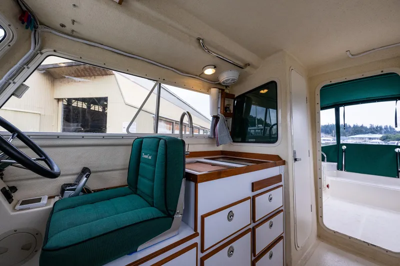 Slide: The Image of Interior of a 2006 C-Dory 25' Tomcat Catamaran with green seating and wooden cabinetry. - 24