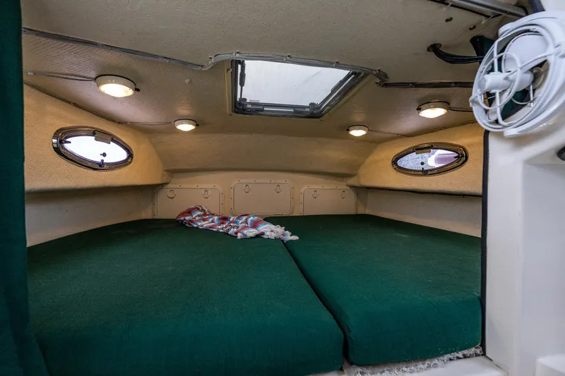 Slide: The Image of Cozy cabin interior of 2006 C-Dory 25' Tomcat Catamaran with green cushions and portholes. - 28
