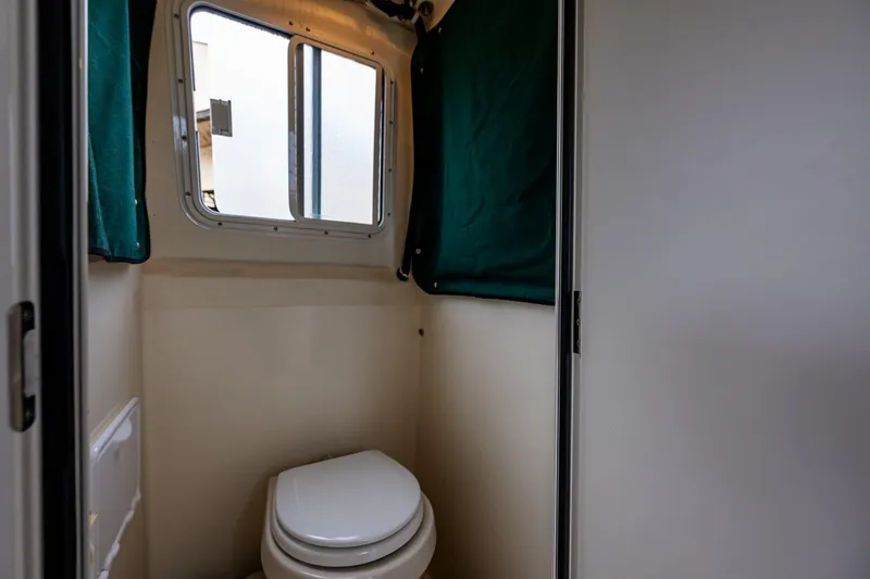 Slide: The Image of 2006 C-Dory 25' Tomcat Catamaran bathroom with window and green curtain. - 29