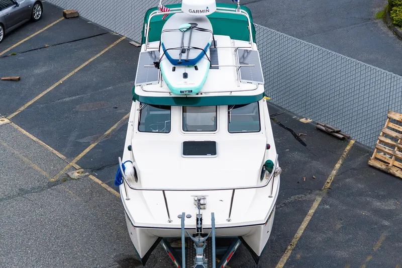 Slide: The Image of 2006 C-Dory 25' Tomcat Catamaran with paddleboard on top, parked in a lot. - 3