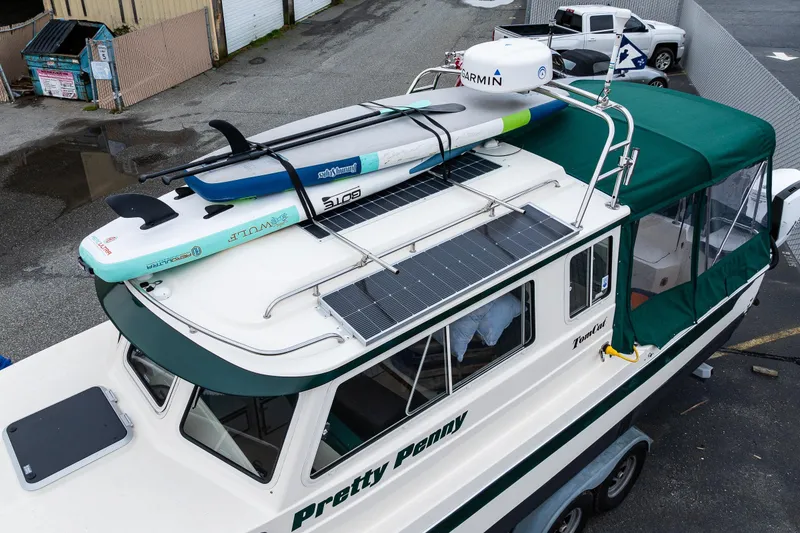 Slide: The Image of 2006 C-Dory 25' Tomcat Catamaran with paddleboards on roof, docked in marina. - 6