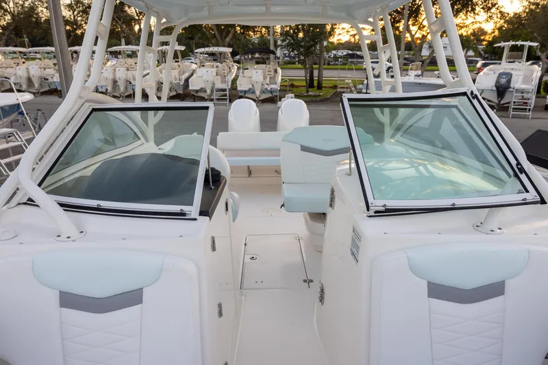 Slide: The Image of 2020 Robalo R247 Dual Console boat interior with seating and windshield, parked outdoors. - 13