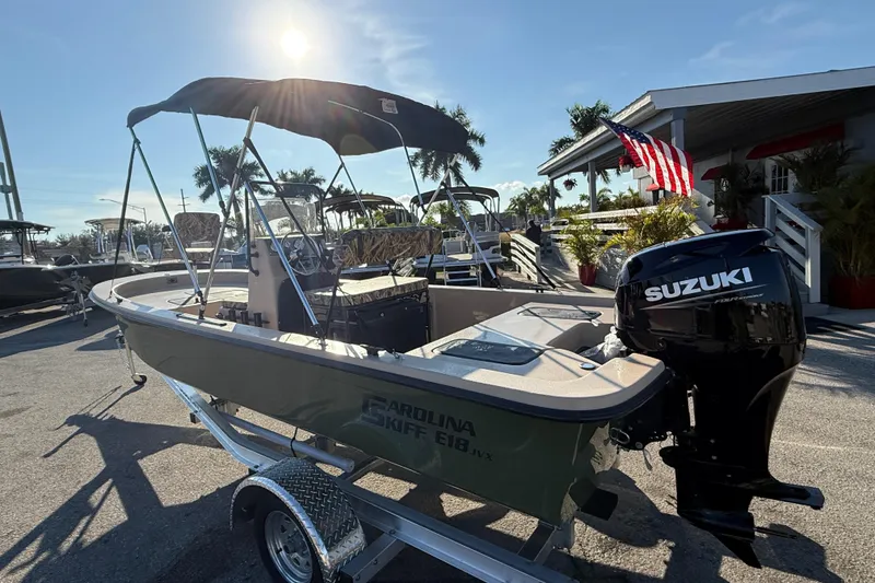 Slide: The Image of 2025 Carolina Skiff E18 JVX CC Sportman Edition boat with Suzuki engine, parked outdoors. - 10