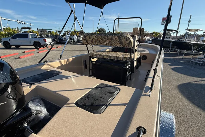 Slide: The Image of 2025 Carolina Skiff E18 JVX CC Sportman Edition boat with camo seating, parked outdoors. - 11