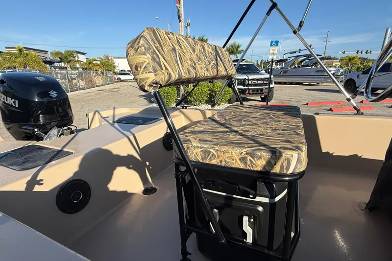 Slide: The Image of 2025 Carolina Skiff E18 JVX CC Sportman Edition boat interior with camo seating and Suzuki outboard motor. - 13