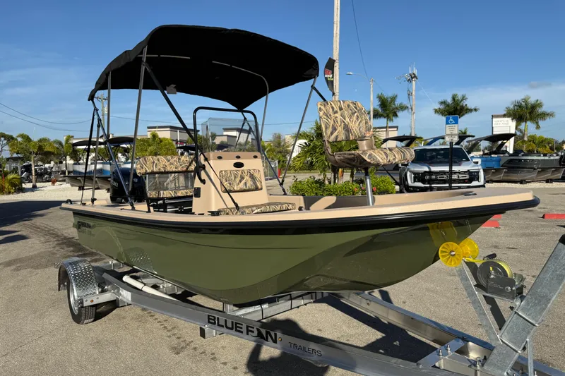 Slide: The Image of 2025 Carolina Skiff E18 JVX CC Sportman Edition boat on trailer, camo seats, sunny day. - 5