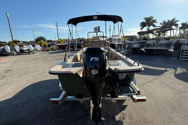 Slide: The Image of 2025 Carolina Skiff E18 JVX CC Sportman Edition boat with 75 HP engine, parked outdoors. - 8