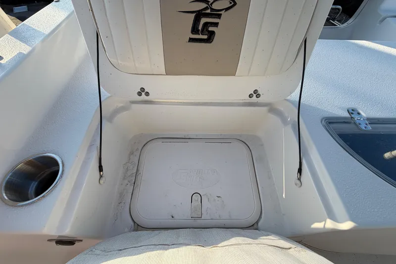 Slide: The Image of 2016 Carolina Skiff 218 DLV boat storage compartment with logo and cup holder. - 57