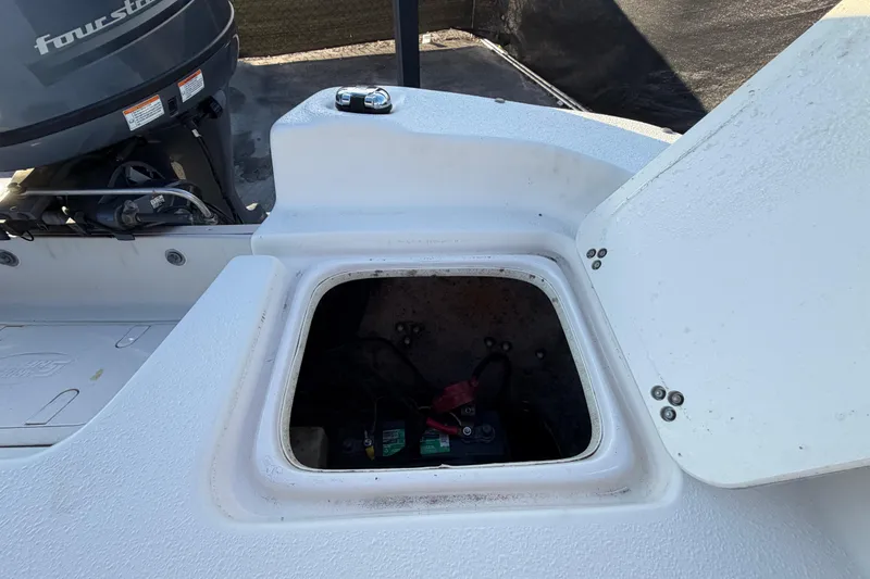 Slide: The Image of 2016 Carolina Skiff 218 DLV boat with open storage compartment and visible motor. - 63