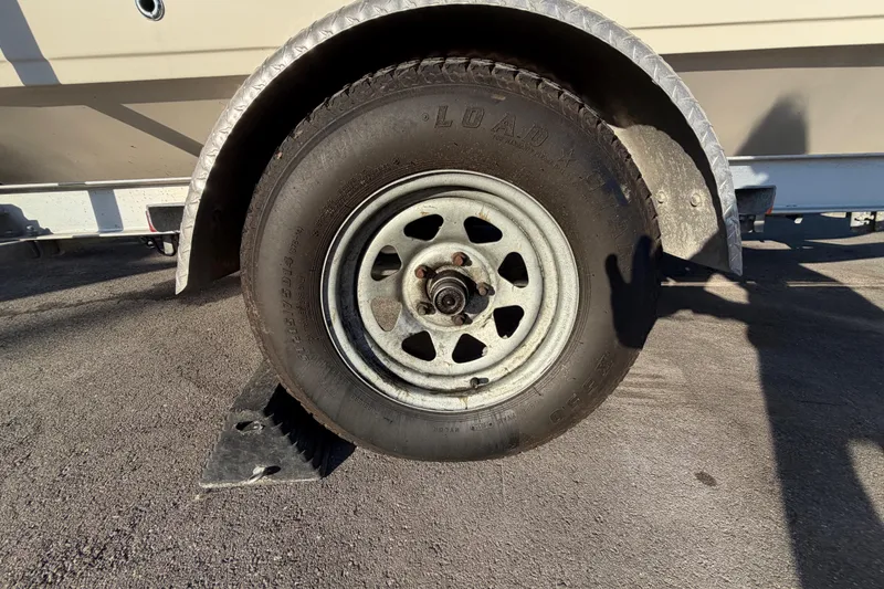 Slide: The Image of Trailer wheel of a 2016 Carolina Skiff 218 DLV boat on pavement. - 67