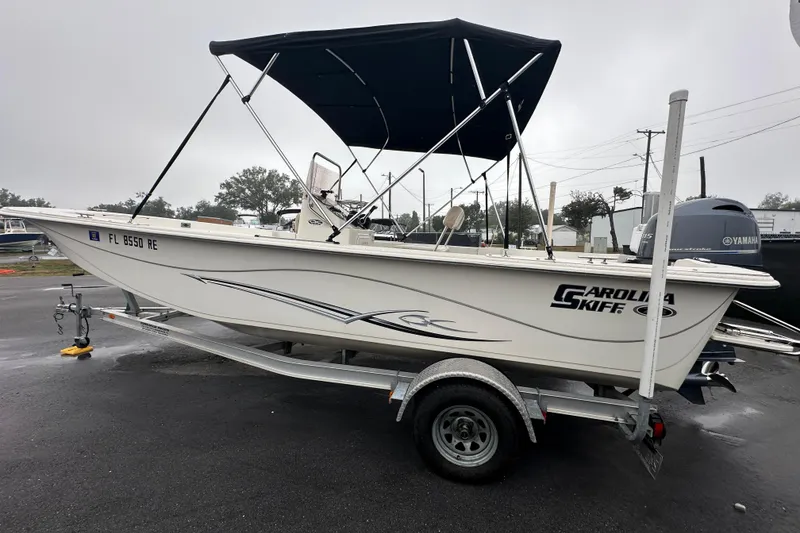 Slide: The Image of 2016 Carolina Skiff 218 DLV boat on trailer with canopy, parked outdoors. - 9