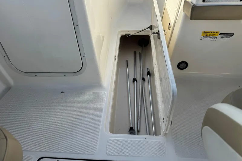 Slide: The Image of 2016 Key West 211 Dual Console boat storage compartment with metal rods inside. - 23