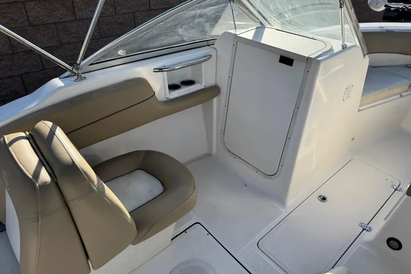 Slide: The Image of 2016 Key West 211 Dual Console interior with beige seating and storage compartments. - 25