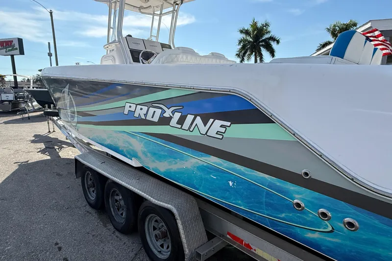 Slide: The Image of 2016 Pro-Line 35 Super Sport boat on trailer, vibrant graphics, sunny day, palm trees in background. - 11