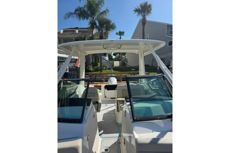 Slide: The Image of 2021 Boston Whaler 240 Vantage boat with dual consoles and a hardtop, docked near palm trees. - 21