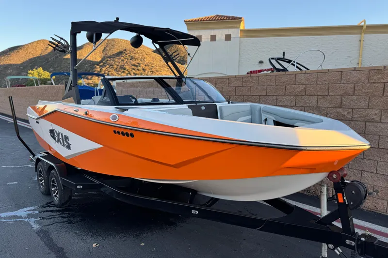 Slide: The Image of 2023 Axis T220 boat in vibrant orange and white, parked on a trailer. - 1