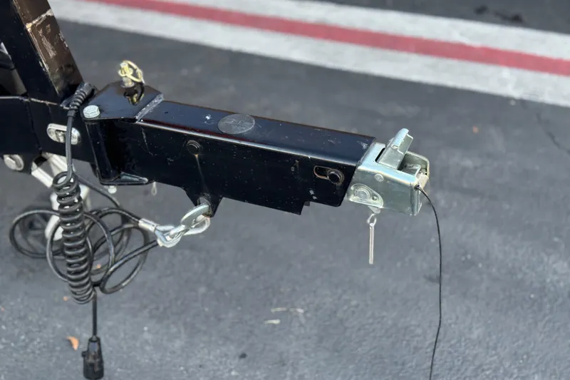 Slide: The Image of Trailer hitch of 2023 Axis T220 on asphalt, featuring safety chains and wiring. - 34