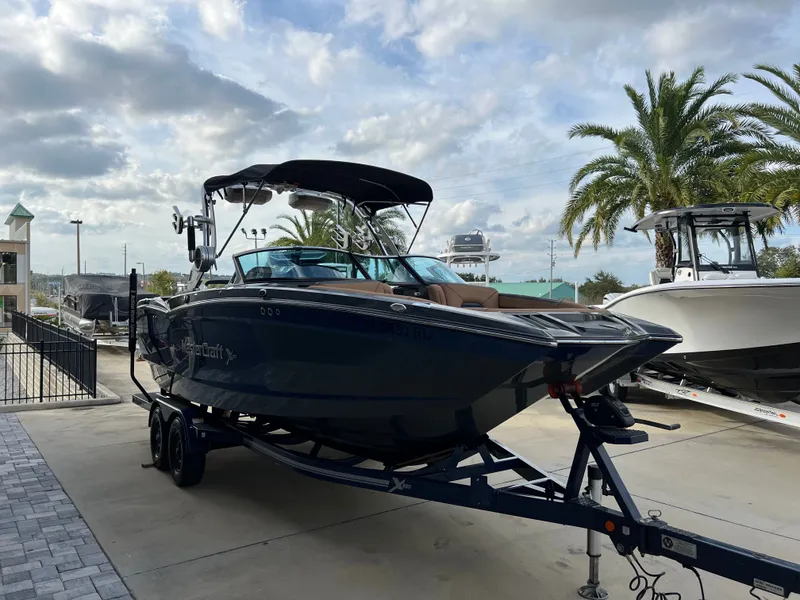 Slide: The Image of 2019 MasterCraft XStar boat on trailer under palm trees. - 8