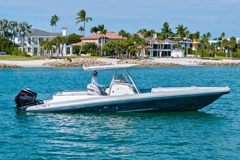 The Image of A 2014 Airship 330 boat cruising near a tropical shoreline with luxury homes. - 0