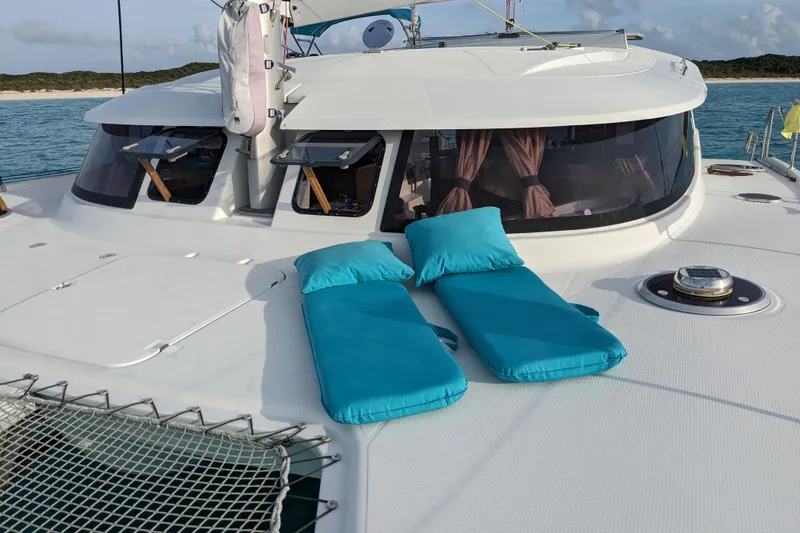 Slide: The Image of 2012 Fountaine Pajot Lipari catamaran with turquoise cushions on deck, anchored near a scenic coastline. - 16