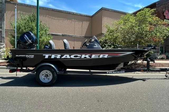 The Image of 2026 Tracker Super Guide V-16 SC boat on trailer, parked outdoors. - 0