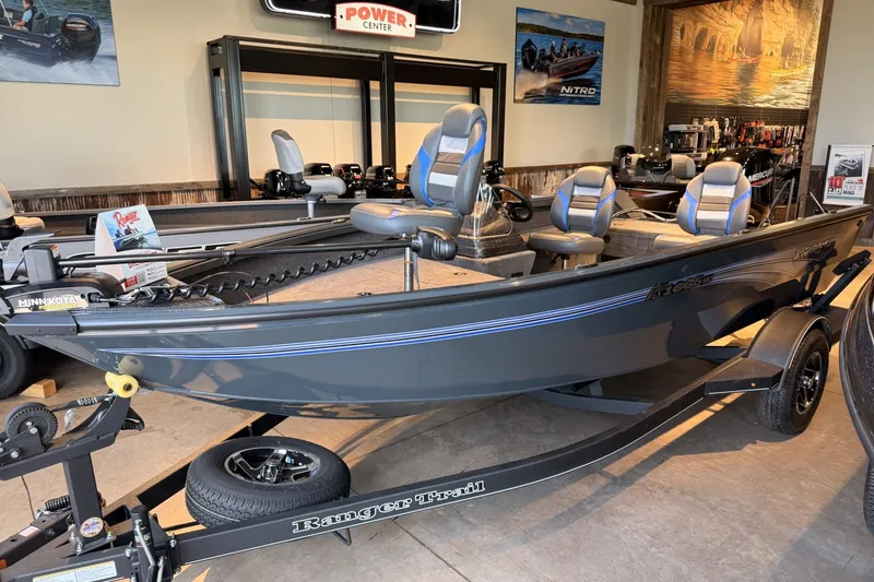 Slide: The Image of 2026 Ranger VS1665SC fishing boat displayed in showroom with blue seats and trailer. - 2
