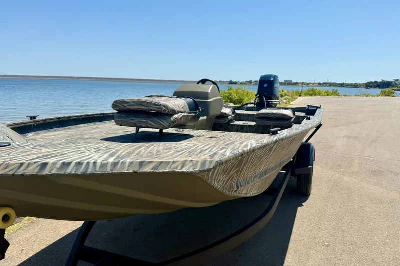 Slide: The Image of 2026 Tracker Grizzly 1754 SC boat on trailer by a lake under clear blue sky. - 16