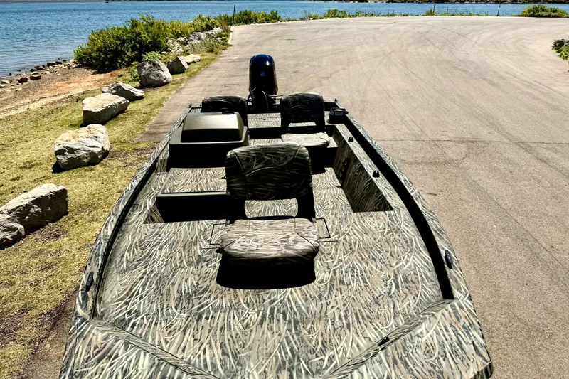 Slide: The Image of 2026 Tracker Grizzly 1754 SC boat with camouflage design near a scenic lakeside. - 14