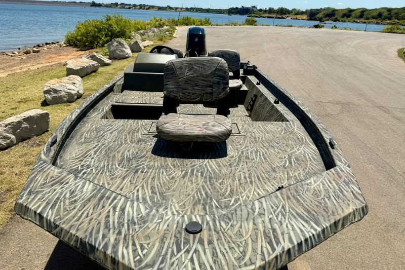 Slide: The Image of 2026 Tracker Grizzly 1754 SC boat with camouflage design near a scenic lakeside. - 15