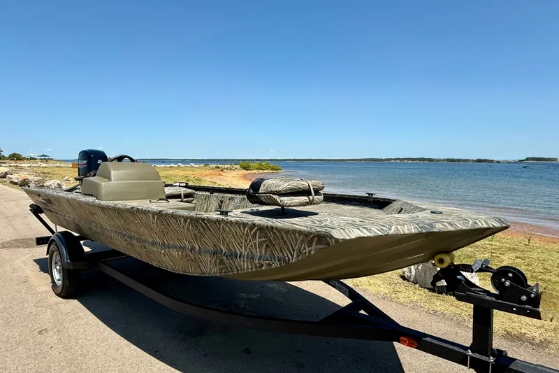 The Image of 2026 Tracker Grizzly 1754 SC boat on trailer by a scenic lakeside. - 0