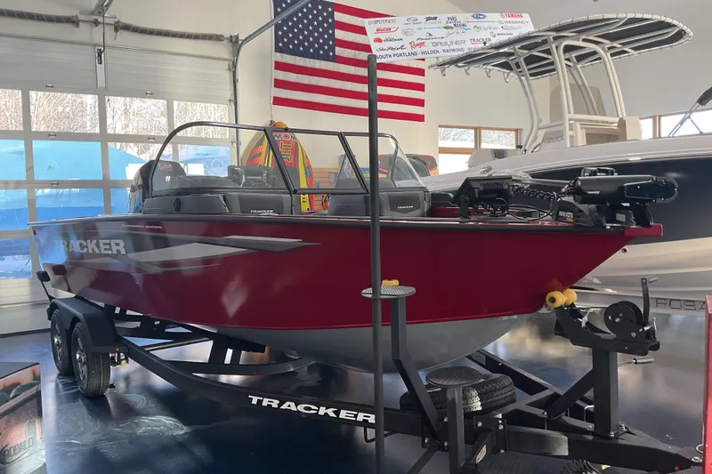 The Image of 2026 Tracker Targa V-19 Combo boat in showroom, red exterior, American flag backdrop. - 1