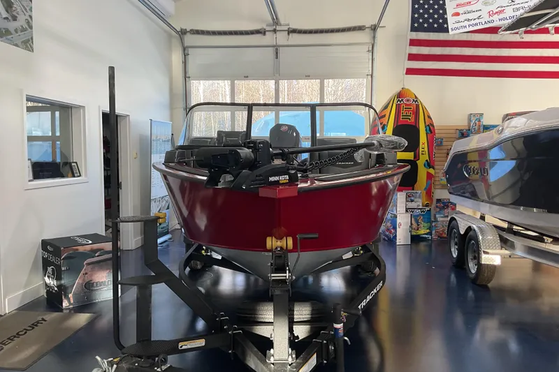 Slide: The Image of 2026 Tracker Targa V-19 Combo boat in showroom, red exterior, American flag displayed. - 2