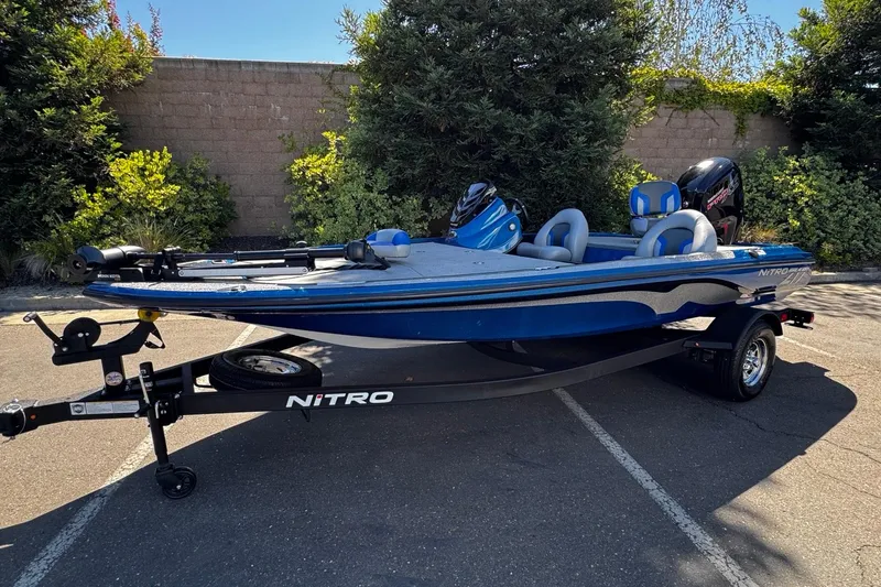 Slide: The Image of Blue 2026 Nitro Z17 boat on trailer, parked outdoors with lush greenery background. - 1