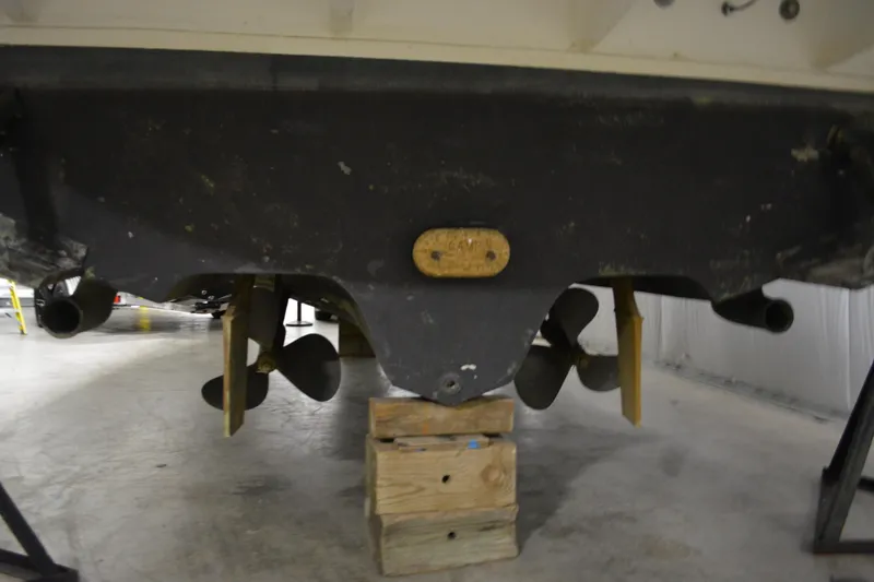 Slide: The Image of 2006 Sea Ray 290 Amberjack boat underside with propellers and rudders in a storage facility. - 10