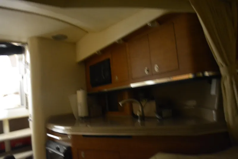 Slide: The Image of 2006 Sea Ray 290 Amberjack interior kitchen with wooden cabinets and modern amenities. - 26