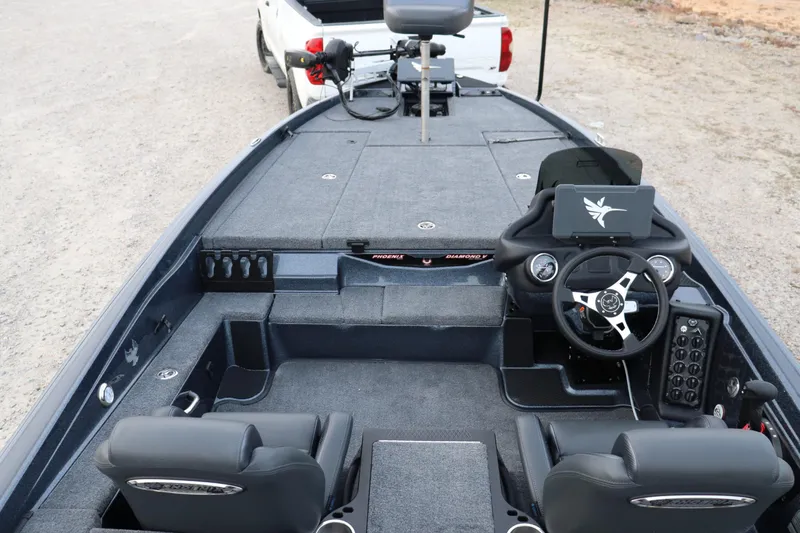 Slide: The Image of 2026 Phoenix 721 ZXL boat interior with steering wheel and seating, parked on gravel. - 14