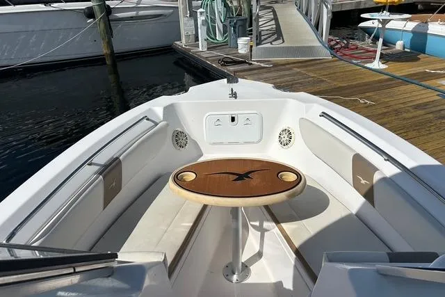 Slide: The Image of 2018 Pro-Line 23 Dual Console boat interior with seating and wooden table at dock. - 8