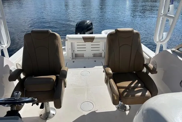 Slide: The Image of 2018 Pro-Line 23 Dual Console boat interior with two brown seats and water view. - 9