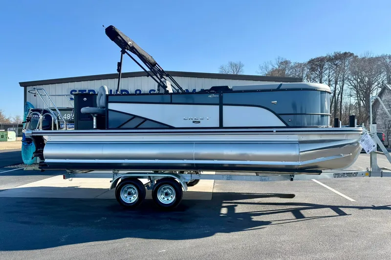 Slide: The Image of 2026 Crest Conquest 210 Fish pontoon boat on trailer, parked outdoors. - 12