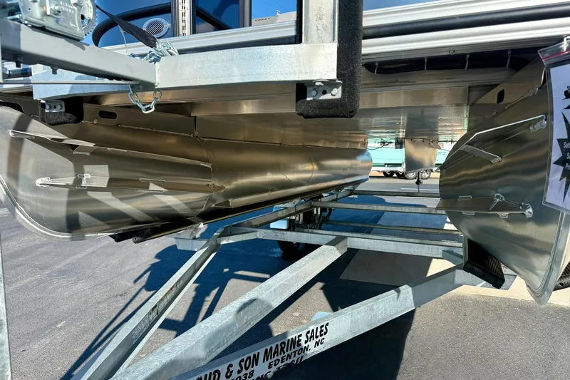 Slide: The Image of 2026 Crest Conquest 210 Fish pontoon boat on trailer, showcasing sleek aluminum pontoons. - 14