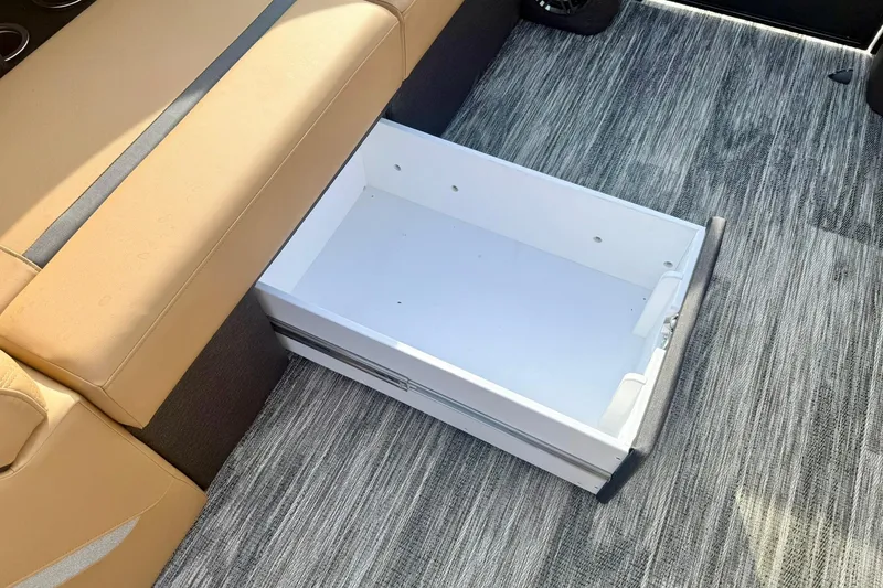 Slide: The Image of 2026 Crest Conquest 230 SLRC boat interior with open storage drawer under tan seating. - 18