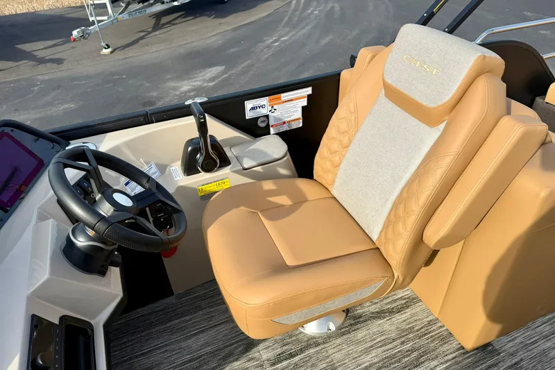 Slide: The Image of Captain's seat and steering of 2026 Crest Conquest 230 SLRC boat, featuring tan upholstery. - 26