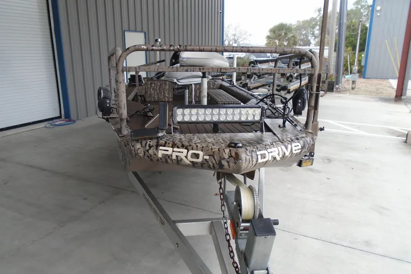 Slide: The Image of 2021 Pro-Drive SBX Series 17' boat on trailer, camo design, parked in industrial area. - 5