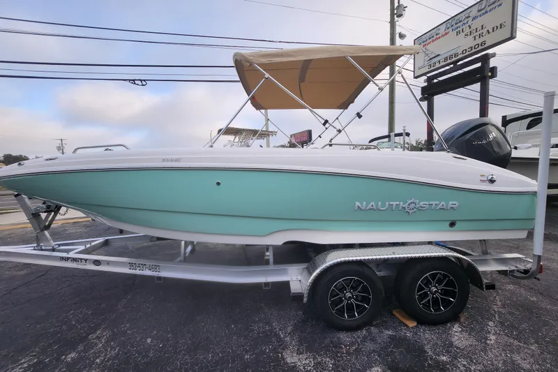 The Image of 2026 NauticStar 203 SC boat on trailer with canopy, displayed outdoors. - 0